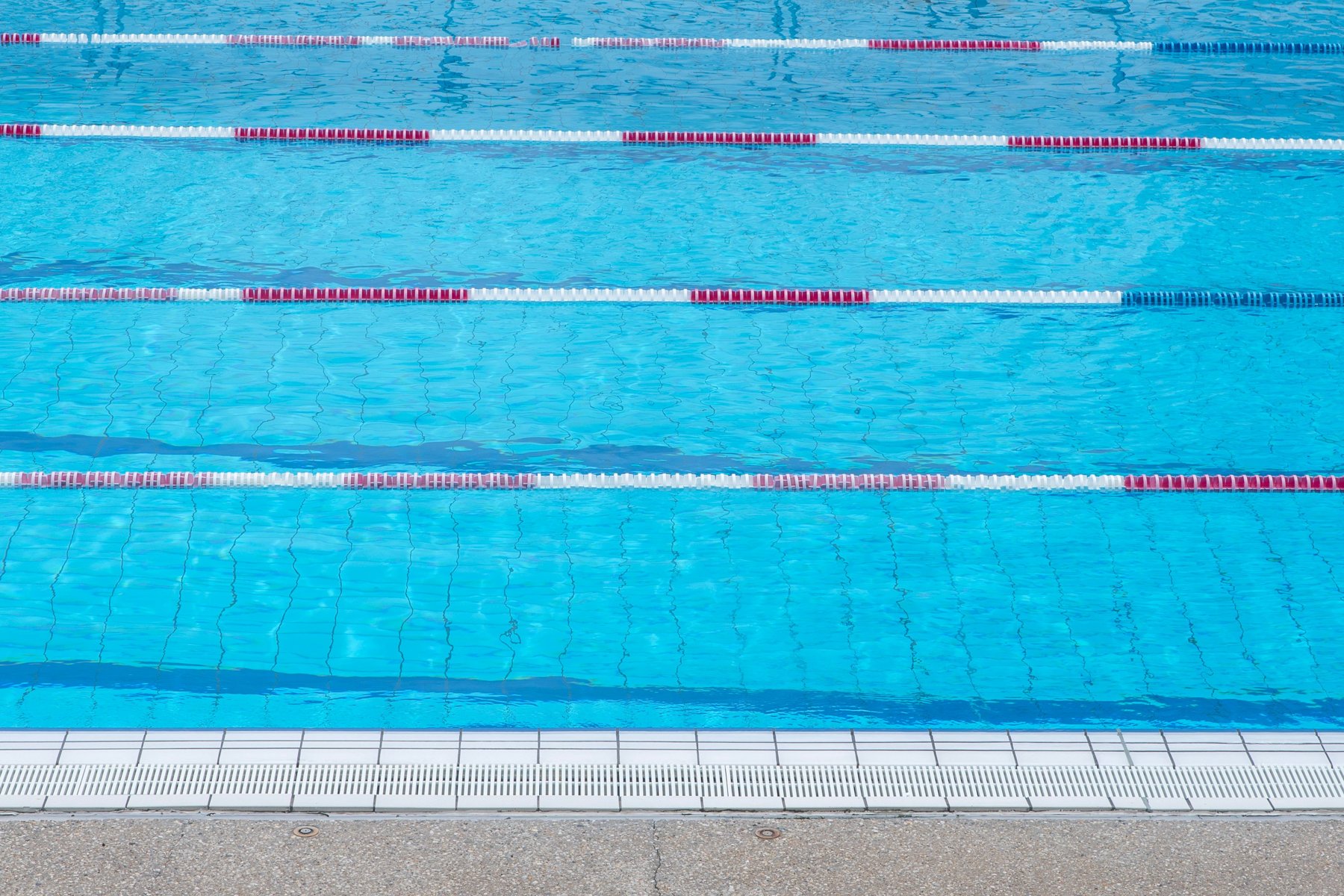 Blue pool water divided by swimming lane ropes